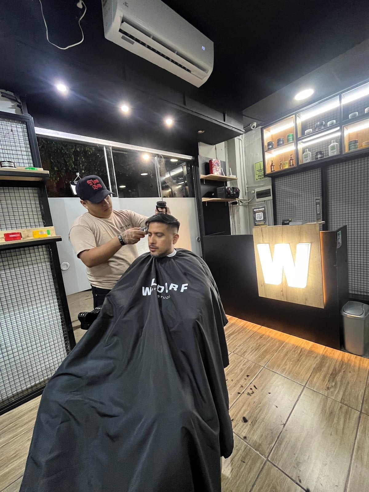 Barbero de Waldorf trabajando un corte junto al logo W iluminado